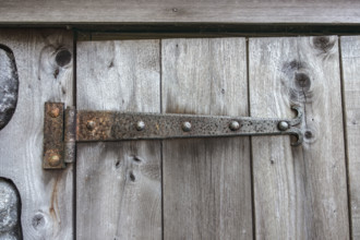 Rusted door hinge on weathered door