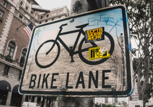 Dirty bike lane sign with graffiti