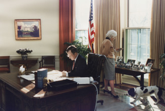 U.S. President George H.W. Bush working at his desk in the Oval Office as U.S. First Lady Barbara