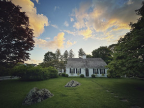 Bow roof cape house and front yard against sunset sky