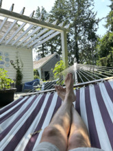 View of mid-adult man's bare legs and feet while relaxing in hammock on summer day