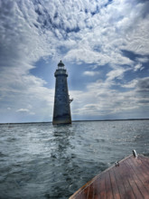 Lighthouse viewed from bow of vintage motor boat