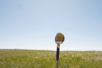 Buried petroleum pipeline warning sign in rural field