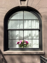 Flower arrangement on sill of residentail apartment's arched window, New York City