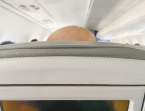 Top of man's bald head in airplane seat, rear view