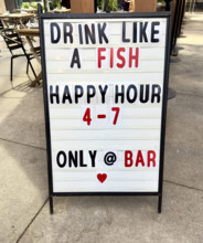 Happy hour sign on urban sidewalk, New York City