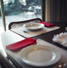 Two empty plates on a dinner table near sliding patio door
