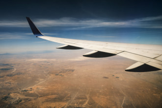Commercial airplane wing viewed from passenger window at dusk