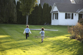 Rear view of two young boys running on a residential lawn