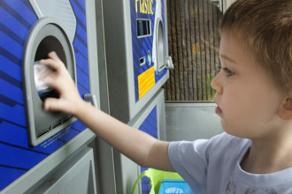 Young boy recycling cans in recycling bin