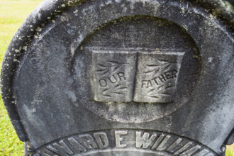 Weathered headstone featuring the words "Our Father"