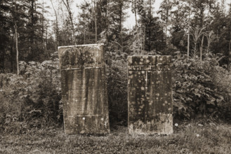 Two weathered headstones at edge of cemetery
