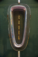 Antique rusted Ford Edsel car grille against green metal background