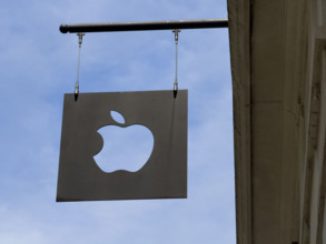 Apple logo sign hanging from building exterior against blue sky, 103 Prince Street, Soho,