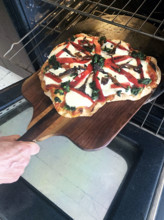 Homemade pizza being put in oven