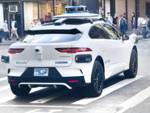 Rear view of Waymo driverless test car, a Jaguar I-PACE electric vehicle and street scene,