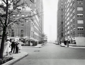 Small group of people standing left with photographer taking photograph of one woman in a hat and