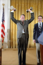 U.S. President, Ronald Reagan lifting weights with George Allen looking on during White House