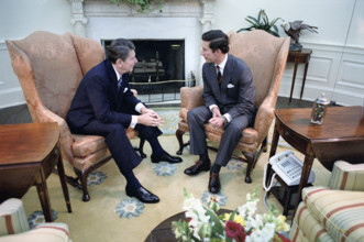 U.S. President Ronald Reagan sitting by fireplace with Prince Charles during visit in the  Oval