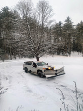 White pickup truck with plow attachment removing snow from residential driveway