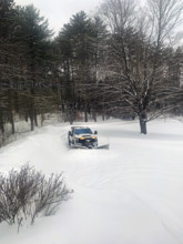 White pickup truck with plow attachment removing snow from residential driveway
