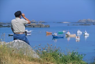 France, Bretagne, Finistere nord, cotes des abers, lilia, autour du phare de l'ile vierge, homme scrutant le paysage avec des jumelles,