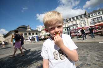 France, Bretagne, Finistere sud, Cornouaille, Concarneau, face a la ville close, les halles et le marche, enfant degustant une fraise de plougastel, gastronomie, personnage ok, passants, touristes,