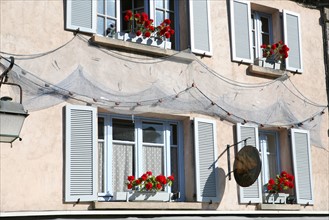 France, Bretagne, Finistere sud, Cornouaille, Concarneau, detail d'une facade de restaurant dans la ville close. filets de peche, geranium, enseigne, lampadaire, fenetres, volets bleus,