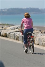 France, Basse Normandie, Manche, saint martin de brehal, plage, sable, femme faisant du velo sur la digue,