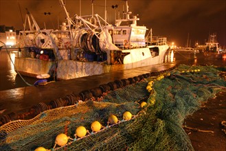 France, Basse Normandie, Manche, Cotentin, Cherbourg, bassin du commerce, centre de maree, debarque de nuit d'un chalutier a quai, lumieres de la ville,