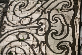France, languedoc roussillon, gard, uzes, ombre de ferronneries d'un balcon sur le sol, paves, vieille ville, habitat traditionnel,