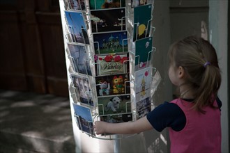 Allemagne (Germany), Berlin, Friedrichshain, immeuble, ancien Berlin Est, enfant devant un presentoir de cartes postales