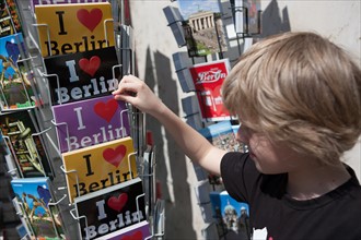Allemagne (Germany), Berlin, Porte de Brandebourg, Friederichstrasse, enfant choisissant des cartes postales,