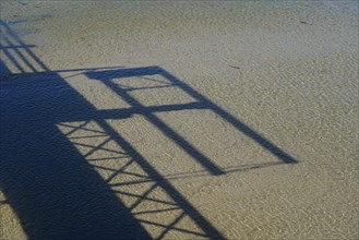 Shadow cast of a footbridge on the sand