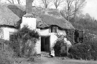 A girl sitting outside a thatched cottage, Minehead, Somerset, c1900