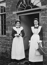 Two housemaids standing in the doorway of a house, Byfield, Northamptonshire, c1896-c1920