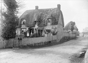 Thatched cottage with its inhabitants standing outside, Ramsbury, Wiltshire, c1860-c1922