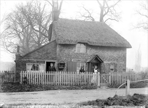 Thatched cottage with the inhabitants standing in the front garden, Uffington, Oxfordshire, 1916