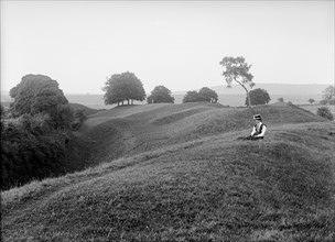 A woman sitting on the external bank at Avebury, Wiltshire, 1908