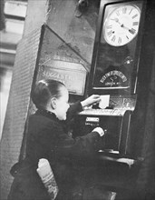 Young boy clocking on at the Trocadero Restaurant, Leicester Square, Westminster, London, c1939. Artist: Unknown