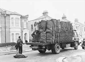 Charringtons delivering sacks of coal down a residential street. Artist: Unknown