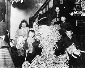 Making party streamers at home, London, c1900. Artist: Unknown