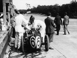 Austin by the pit wall, 500 Mile Race, Brooklands, Surrey, (1931?). Artist: Unknown