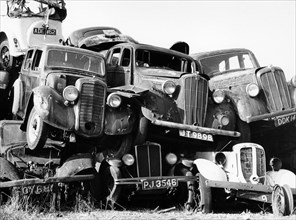 Old cars piled up in a scrapyard, Britain. Artist: Unknown