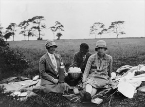 Three women having a picnic in a field, (1920s?). Artist: Unknown