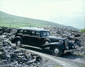 A 1937 Cadillac V16 sedan, photographed among piles of slate. Artist: Unknown