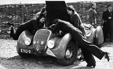 Miss MD Patten looking at the engine of a 1938 Peugeot 402 Special Sport, RAC Rally, 1939. Artist: Unknown
