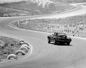 1964 Chevrolet Corvette Stingray on a winding racetrack, (c1964?). Artist: Unknown