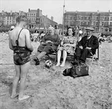 A child photographs his mother and grandparents on the beach, Blackpool, c1946-c1955