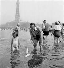 A father and daughter sail a model yacht in the sea, Blackpool, c1946-1955